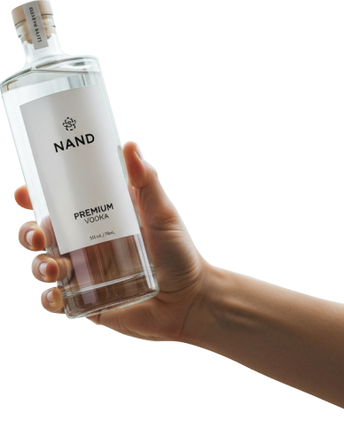 Hand holding a premium clear vodka bottle against a white background