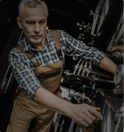 Distillery operator in overalls working at a copper distillation unit