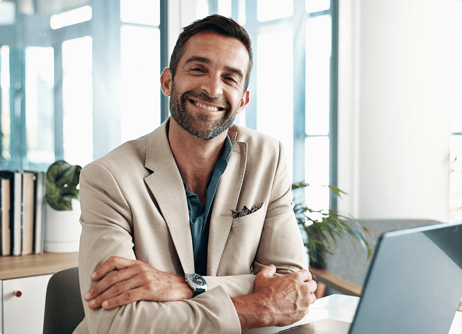 Smiling manager at a desk with a laptop — business portrait