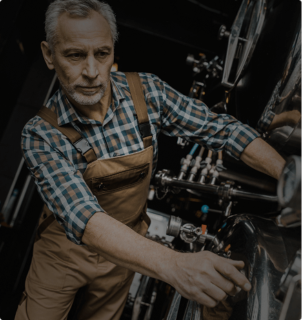 Distillery operator in overalls working at copper distillation equipment