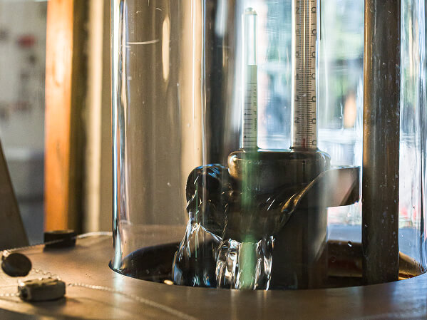 Sight glass with thermometer at the top of a distillation column showing spirit flow