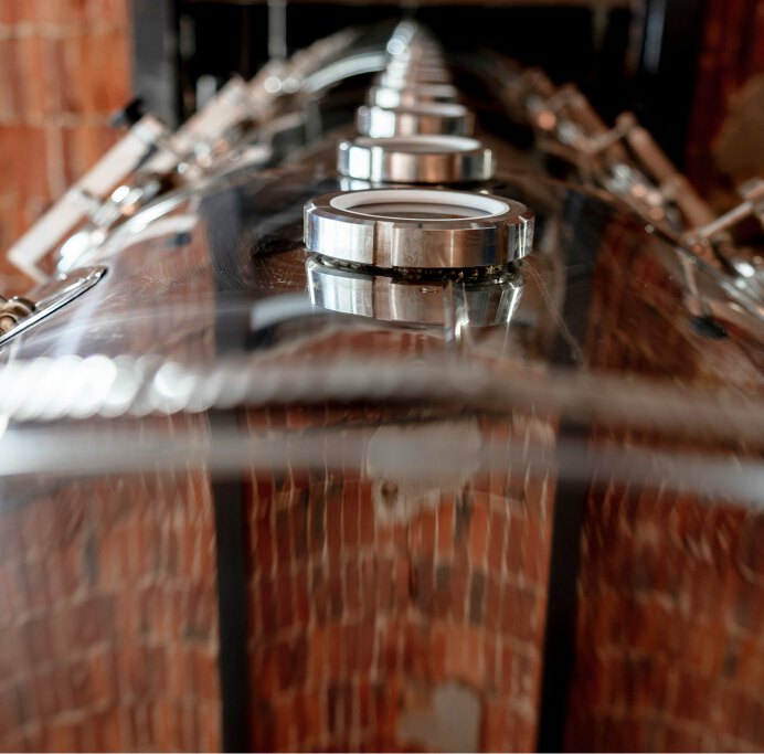 Copper distillation vessels at the Alquora distillery against a brick wall