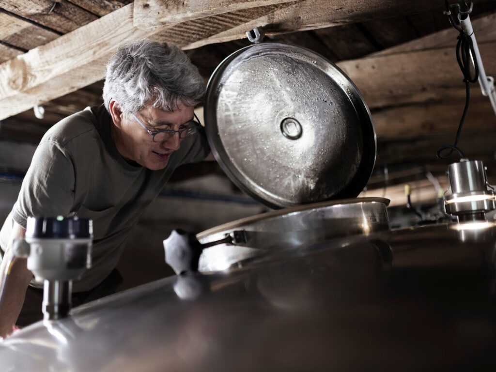 Alquora distiller inspecting the hatch of a fermentation tank