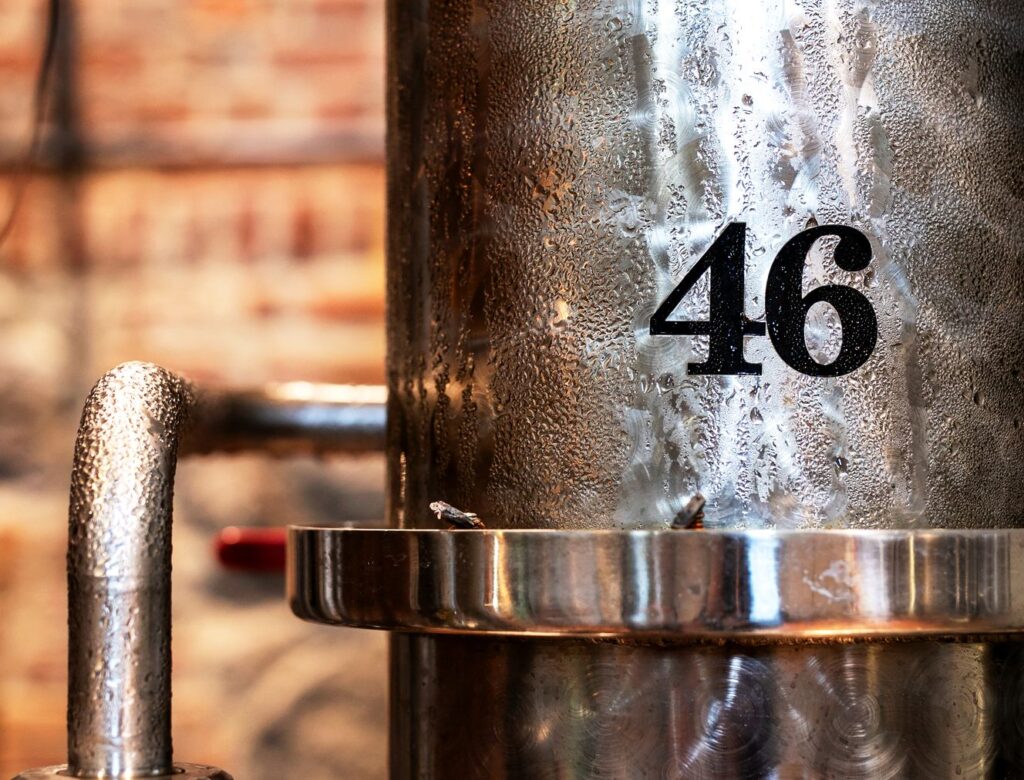 Distillation column marked 46, covered in condensation, with a copper flange
