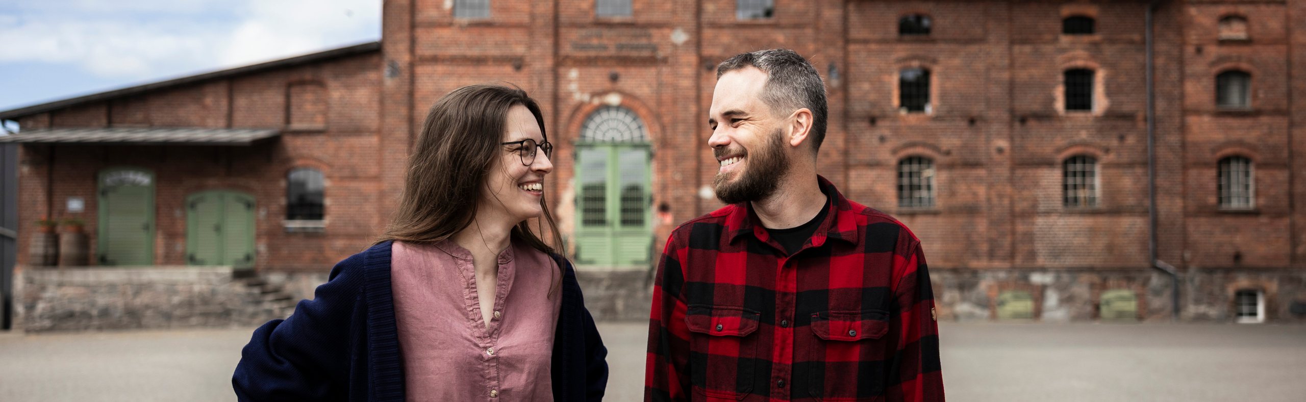 Smiling couple in front of the Alquora distillery brick building