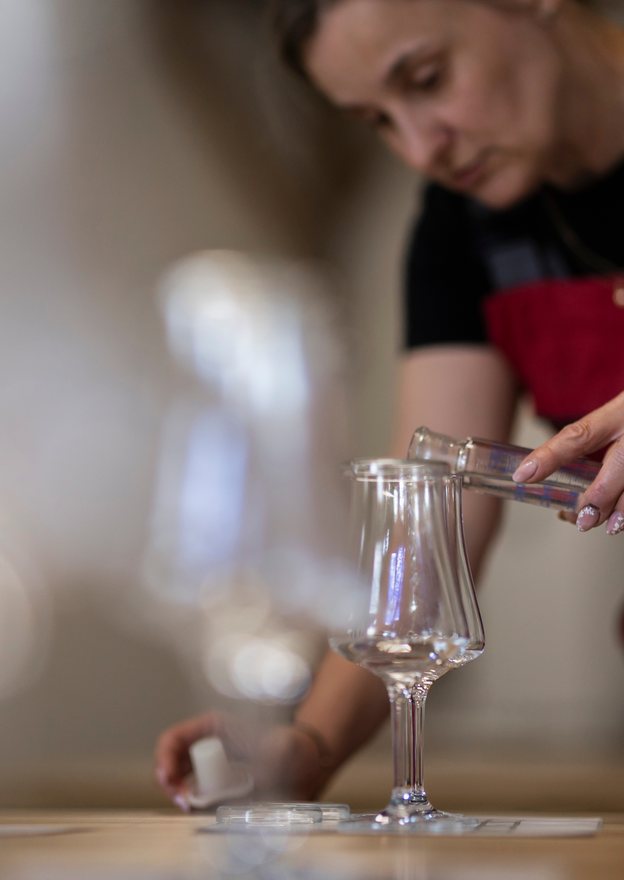 Alquora distillery worker pouring a spirit sample into a tasting glass